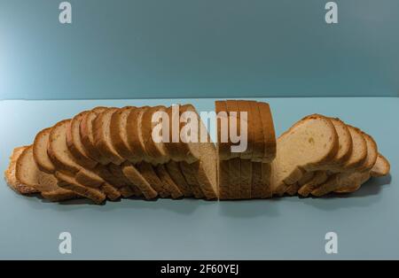 Industrial bread on blue background. Loaf bread. Loaf of bread is a product obtained from cooking the sweet dough of wheat flour. Gluten-based food. Stock Photo