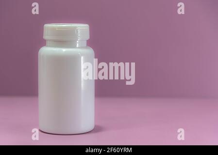 white plastic bottle for medicine on pink background. Medicinal packaging. Bottle for storing pills and pills. Hospital supplies. Stock Photo