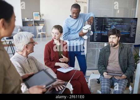 High angle view at contemporary diverse business team sitting in circle during strategy meeting, focus on young businesswoman in center Stock Photo