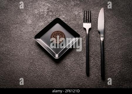 cookies in a black square plate, fork and knife. minimalist still life. the design of tableware and table setting. Stock Photo