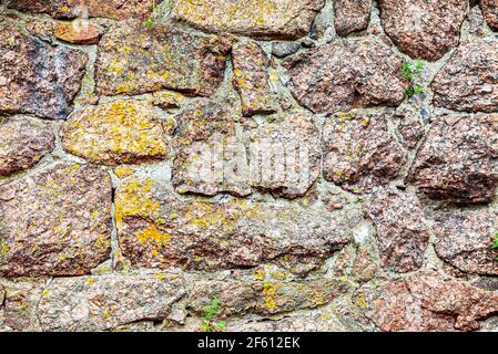 Rough stone wall as creative background texture. Natural stones masonry with uneven seams Stock Photo