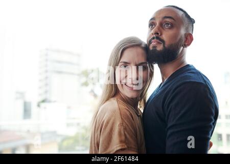Cheerful mixed-race couple in love hugging when standing outdoors Stock Photo