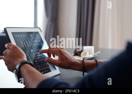 Hands of man using smart home application on tablet computer to control music volume in apartment Stock Photo