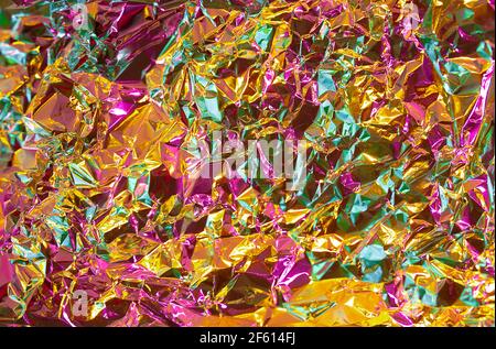 Gold texture effect with pink and green multicolor tint. Futuristic chrome abstract crumled foil paper. Honey gold and juicy pink fusion colors backgr Stock Photo