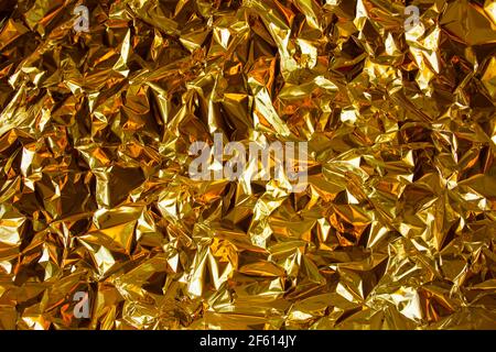 Golden metal chrome foil paper background with bold crumpled texture for fresh and luxury design. Sparkling rich gold luxury background. Stock Photo