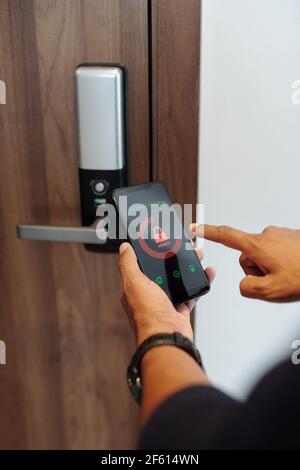 Hands man using security control application on smartphone when locking apartment door Stock Photo