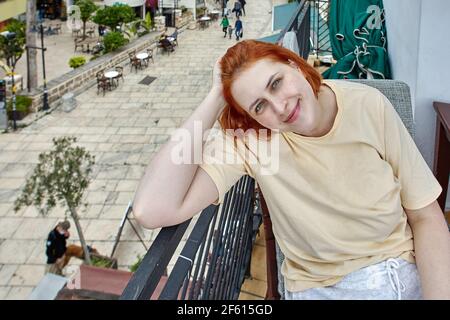 An attractive european woman sits on terrace of summer cafe in old city of Antalya in early spring. Stock Photo