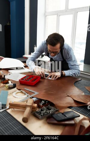 Skilled leather manufacture worker cutting some samples. Stock Photo
