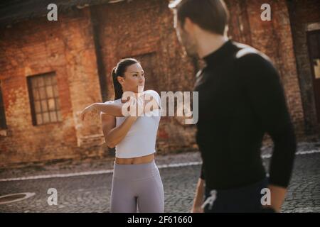 Sporty young woman doing stretching exercise after jogging with her personal trainer Stock Photo