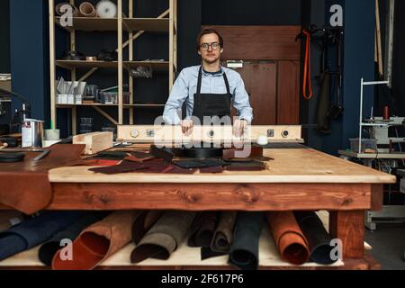 Skilled leather manufacture worker cutting some samples in workshop studio. Stock Photo