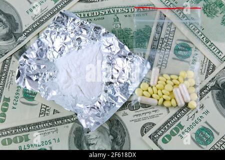 Drugs on a American dollar banknote background. Crime business concept. Cocaine, heroin and pills on cash. Stock Photo