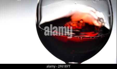 Red wine on grey background, abstract splashing. Copy space for your text. Closeup. Stock Photo