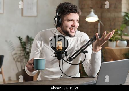 Young man in headphones using microphone and recording podcast or interview for radio Stock Photo
