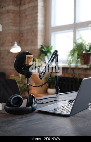 Image of table with laptop microphone and headphones preparing for recording in studio Stock Photo