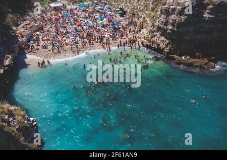 Polignano a Mare, Italy - August 12, 2014: Tourists on summer vacation at the beach Cala Paura, one of most beautiful at Adriatic Sea. The famous sing Stock Photo
