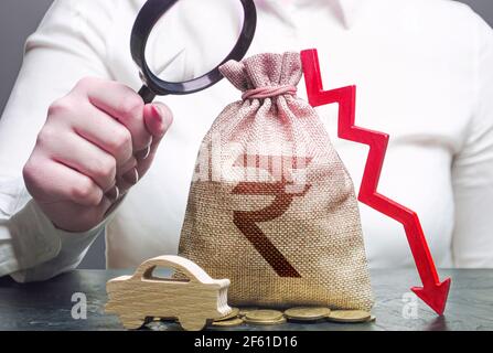 Woman female manager examines a indian rupee money bag with a red down arrow and automobile. Electric vehicle support subsidies. Car insurance, taxes, Stock Photo