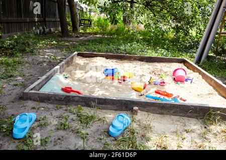 Sandbox outdoor. Children's wooden sandbox with various toys for the game. Summer concept Stock Photo