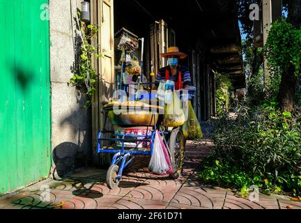 A male street vendor pushes food cart along the street in Talat Noi, Bangkok, Thailand Stock Photo