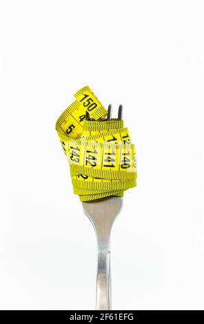 diet concept, fork with yellow measuring tape on white background Stock Photo