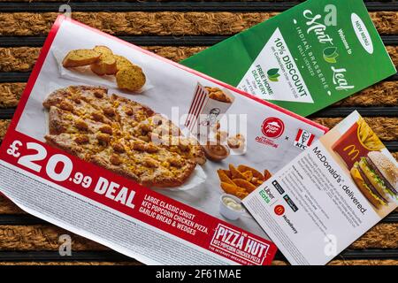 assortment of Junk mail post unsolicited mail for fast food offers takeaways on door mat Stock Photo