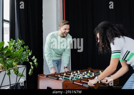 excited businessman playing table football with african american colleague Stock Photo