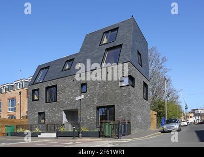 Distinctive new apartment block on Costa Steet, Peckham by WHAT Architecture. Features dark brickwork, black windows and outward-sloping mansard roof. Stock Photo