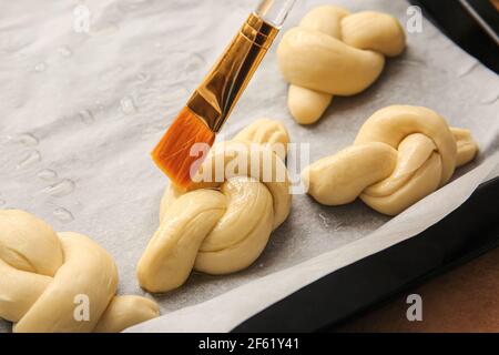 Greasing uncooked garlic buns with oil on color background, closeup Stock Photo