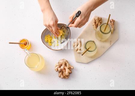 Woman grating ginger on light background Stock Photo