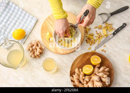 Woman grating ginger on light background Stock Photo