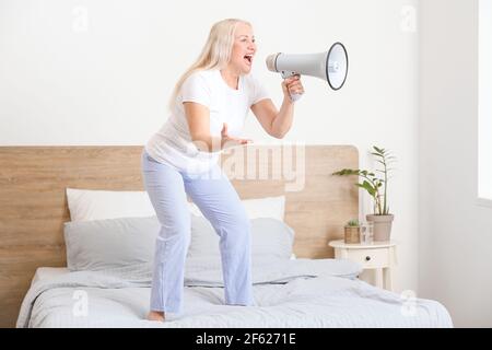 Screaming mature woman with megaphone at home Stock Photo