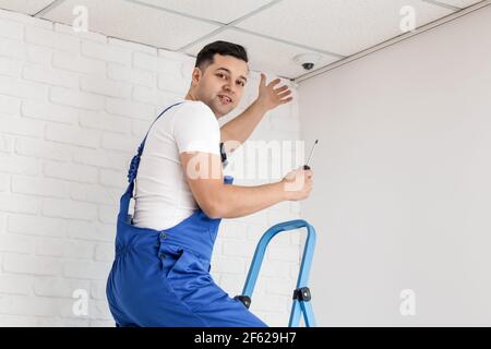 Worker installing CCTV camera in room Stock Photo