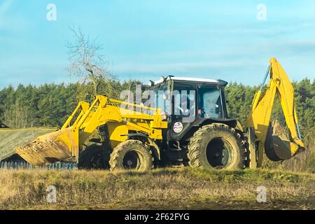Belarus, Minsk region - December 19, 2019: Bulldozer in countryside field against the backdrop of a sunny forest. Stock Photo