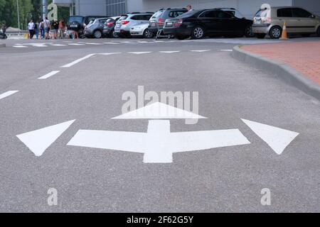 Road marking on asphalt. White arrow marking pointing ahead, left, right on road. Stock Photo