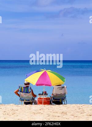 Older couple sitting on beach, Seven Mile Beach, West Bay, Grand Cayman, Cayman Islands, Greater Antilles, Caribbean Stock Photo