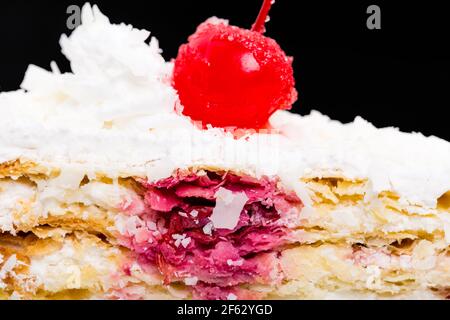 Delicious cake with cocktail cherry and coconuts. Macro. Against black background. Stock Photo