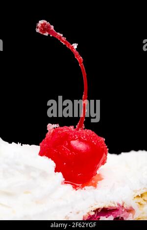Delicious cake with cocktail cherry and coconuts. Macro. Against black background. Stock Photo
