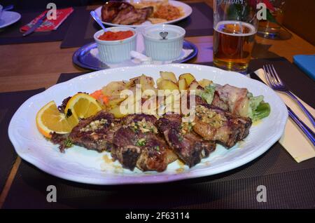 meat dish with fried potatoes and rice on a white plate Stock Photo