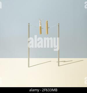 Two clothespins, one bunny shaped, fasten on clothesline against pastel blue and yellow background. Minimalist concept. Square. Stock Photo