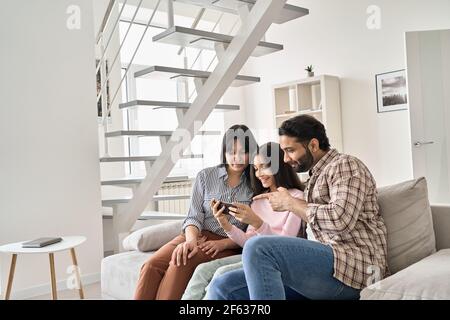 Happy indian family with teen daughter using phone together at home. Stock Photo