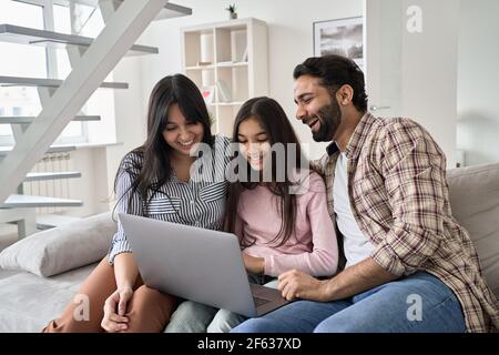 Happy indian family with teenage daughter having fun using laptop at home. Stock Photo