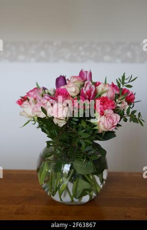 bouquets of roses, cloves and tulips in vase on table with white and grey background Stock Photo