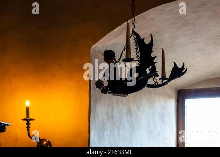 Silhouette of vintage candelabrum depicting mermaid with two unfired candles, and one burning candle on the wall. Stock Photo