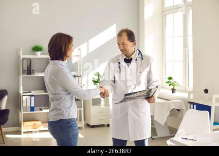 Happy patient shaking hands with mature doctor thanking him for professional help Stock Photo