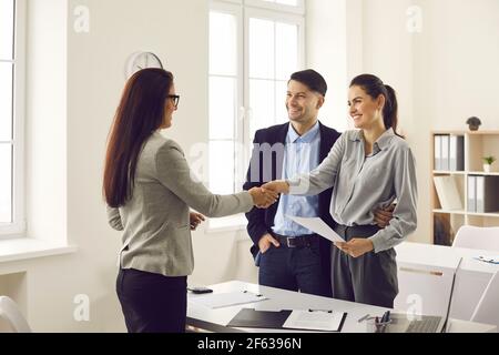 Young smiling couple shaking hands with real estate agent or bank manager Stock Photo