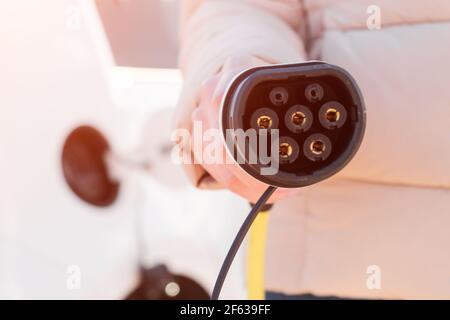 Power Cable for charging of electric vehicle in woman hand at sunlight Stock Photo