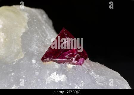 Red spinel crystal, uncut, still set in white host rock matrix. From Mogok region, Myanmar. Black background. Stock Photo