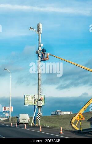 Belarus, Minsk - December 19, 2019: Industrial working men raised on a machine crane mending a power line. Stock Photo