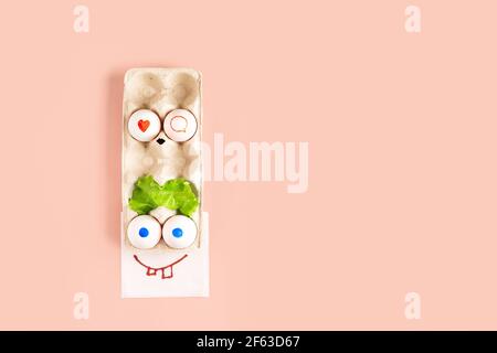 Colorful funny face made of easter eggs on pink background with copy space Stock Photo