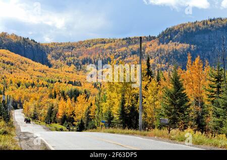 Beautiful, vivid, fall colors are seen beside a road and covering most of North Western Mountains seen in this photo. Stock Photo