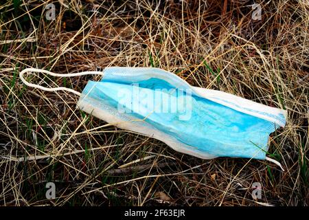 Discarded facemask face mask for covid 19 coronavirus in weeks garbage trash Stock Photo